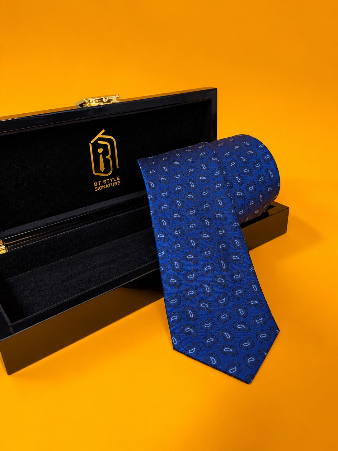 Blue Prestige royal blue paisley necktie resting in an open black gift box