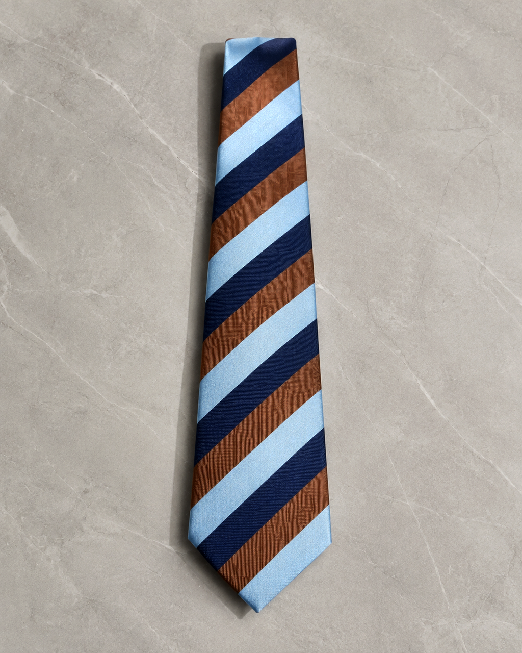 Regatta striped microfiber necktie laid flat on a pale marble surface