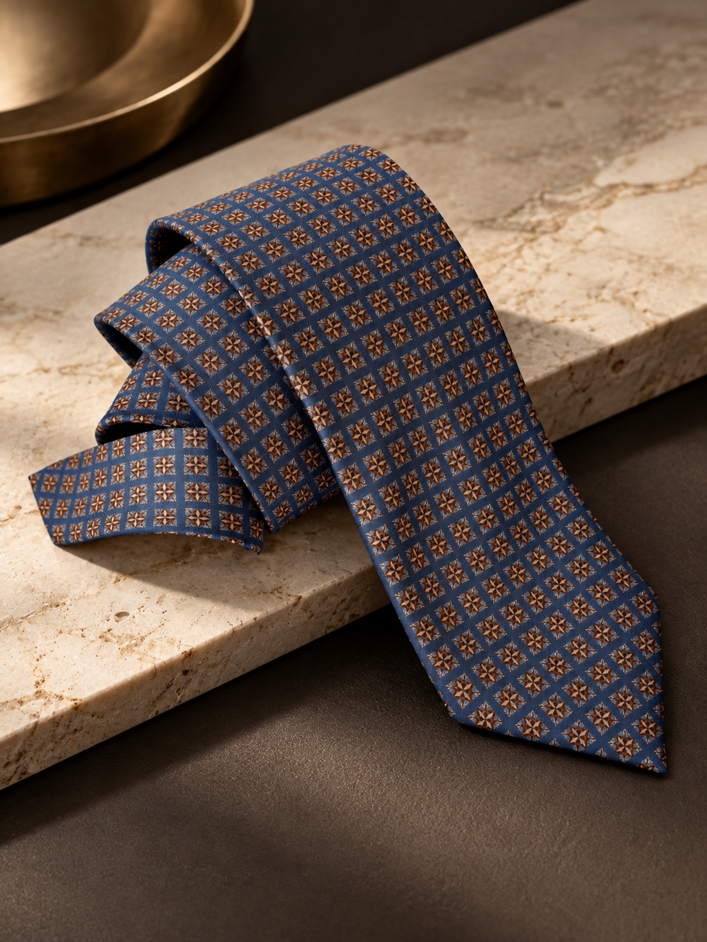 Windsor slate-blue medallion necktie draped over a marble ledge
